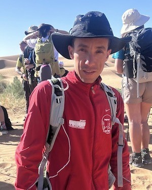 Rdouane, mountain guide, smiling on the trail with a group behind him