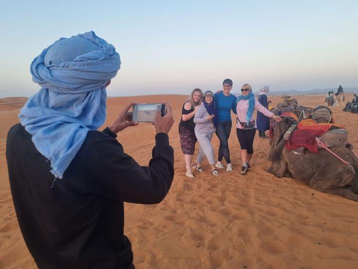 Guests posing on the dunes while a guide takes a photo