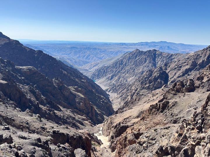 A rocky gorge opening towards a distant blue lake and the plains