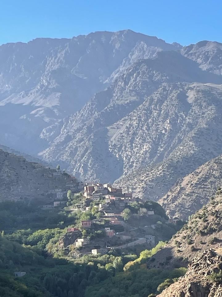 A village lit by morning sun below steep mountains