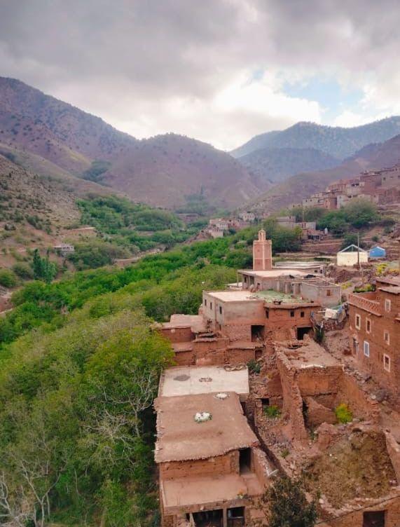 The village of Tamazirt: mud-brick houses and a mosque tower among green trees
