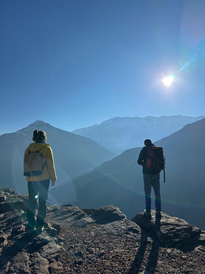 Two hikers looking out over a mountain ridge in bright sun