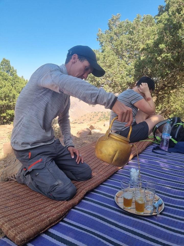 Mint tea poured on a rug among trees on the trail