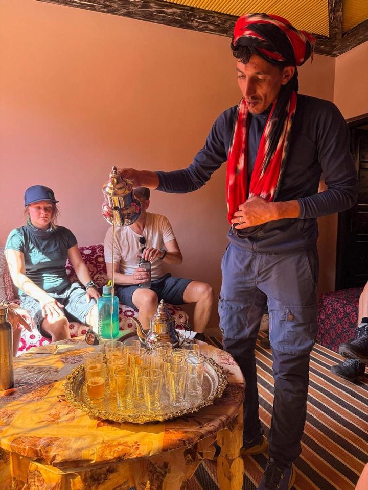 A guide pouring tea for guests in a mountain lodge