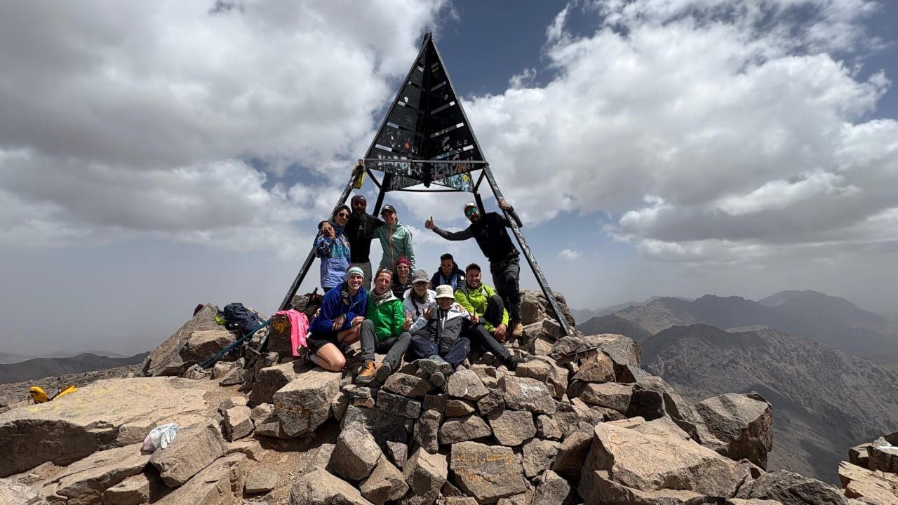 A group of hikers at the summit marker of Toubkal